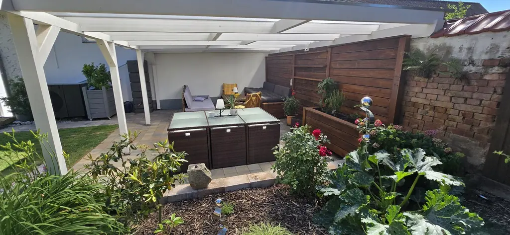 Terrasse unter der Pergola mit Blumenbeet